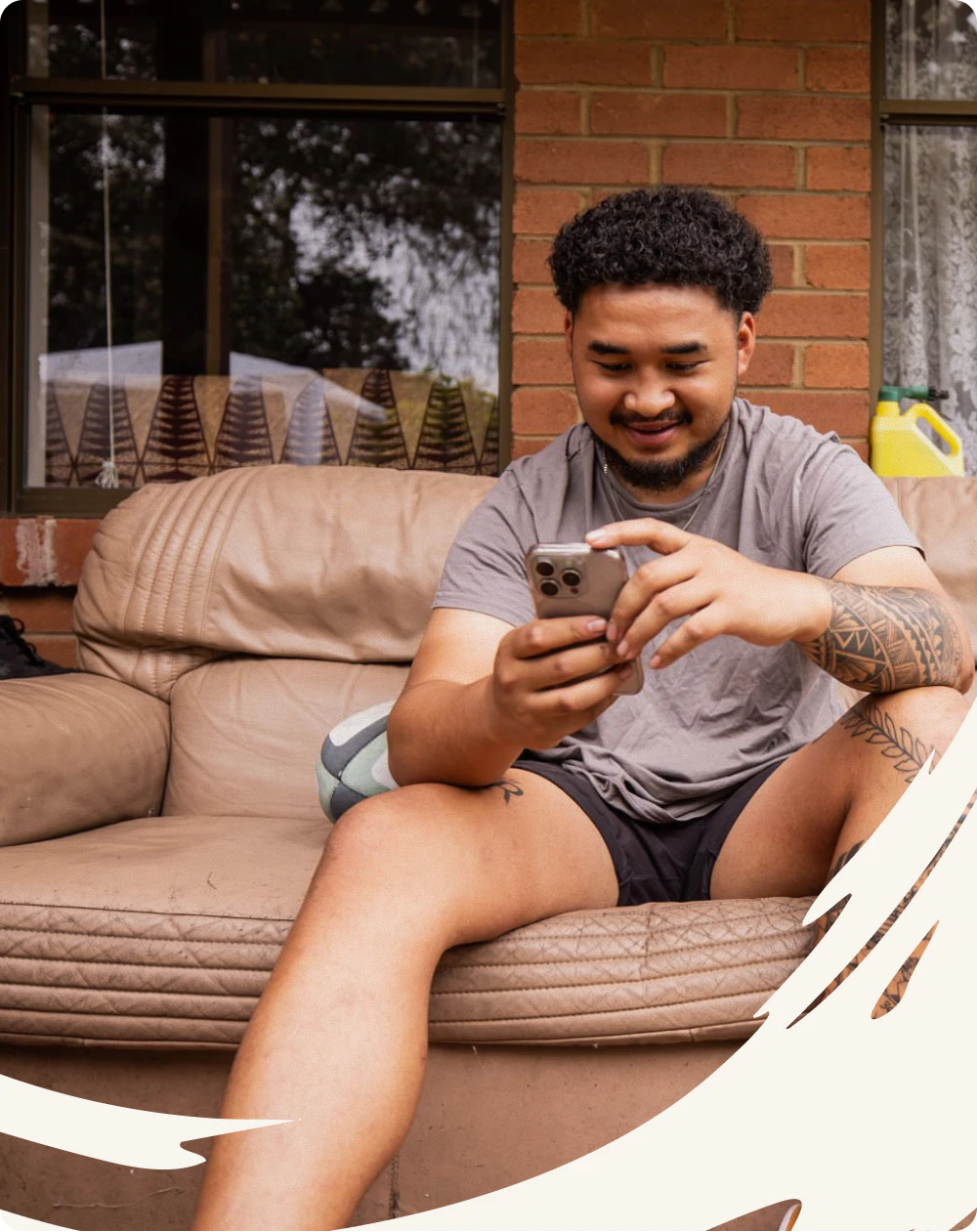 A young man on a couch on his porch, smiling at his phone as he explores what’s next